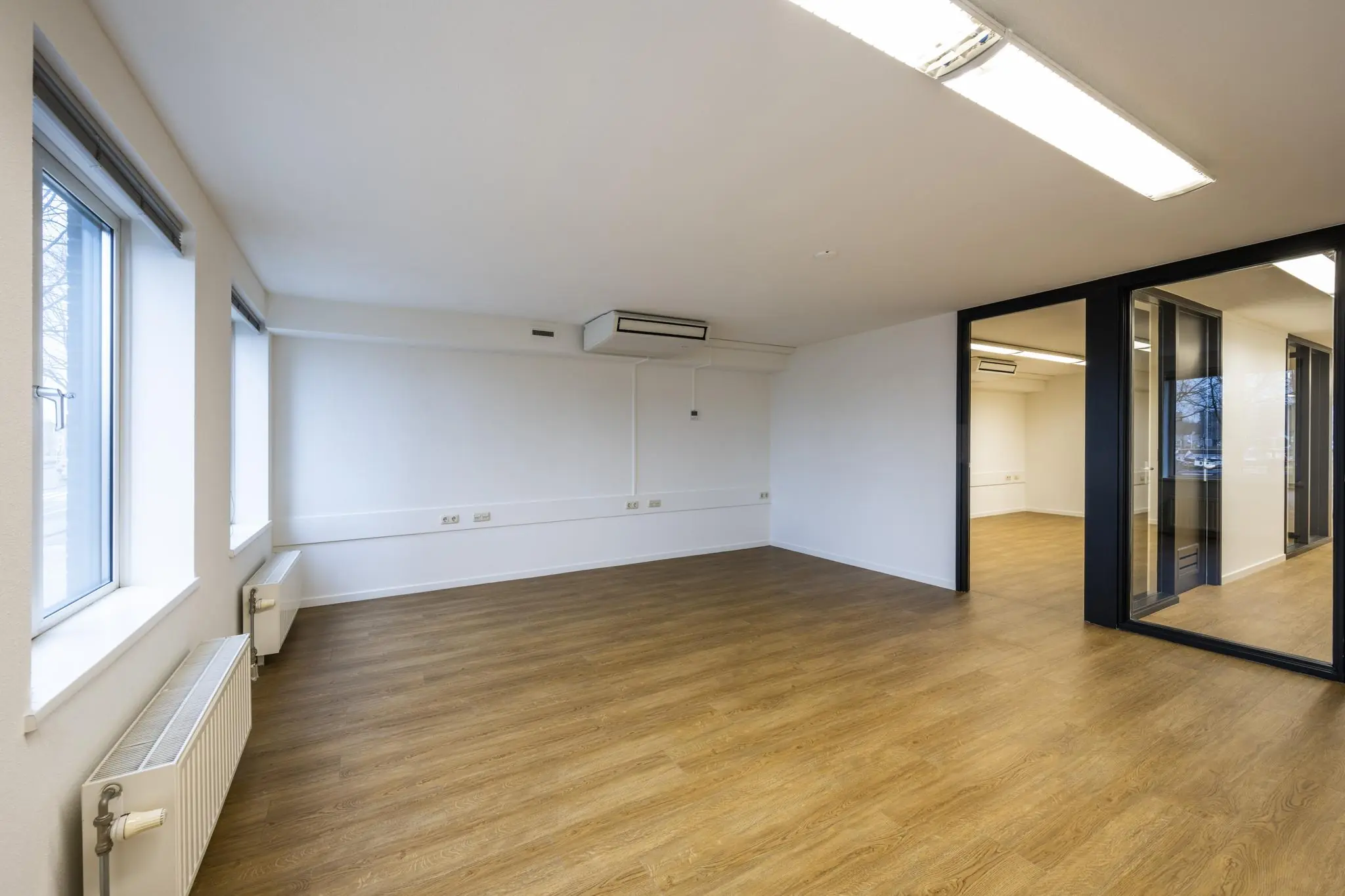 Licht en modern kantoorinterieur aan de Prins Hendrikkade met houten vloer, grote ramen en glazen scheidingswanden.